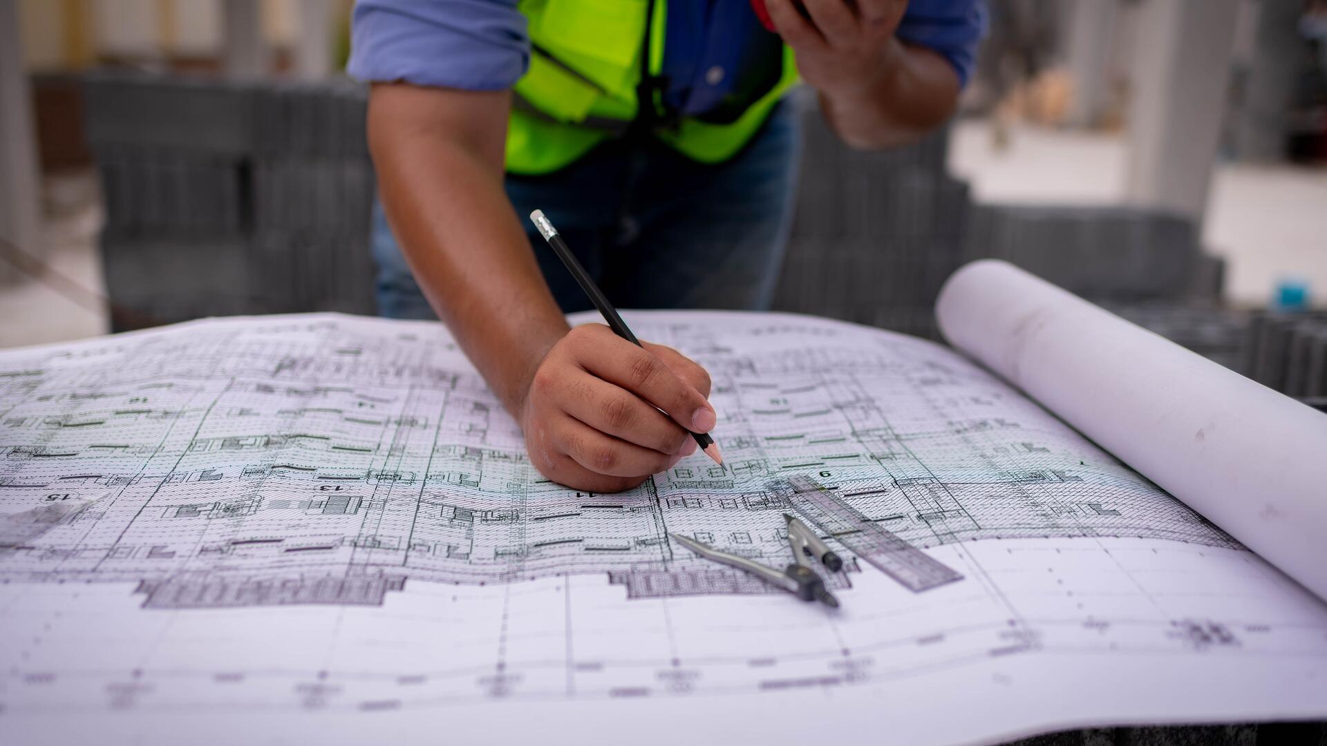 Registered surveyor marking up strata title blueprint on Singapore construction site
